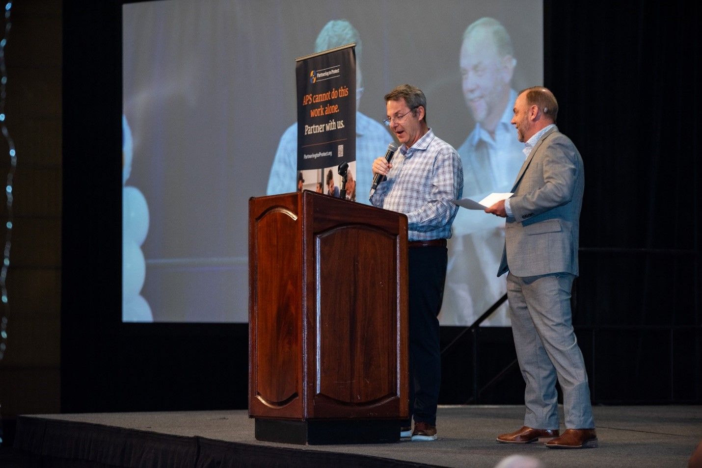 Two men at a speaking at a podium