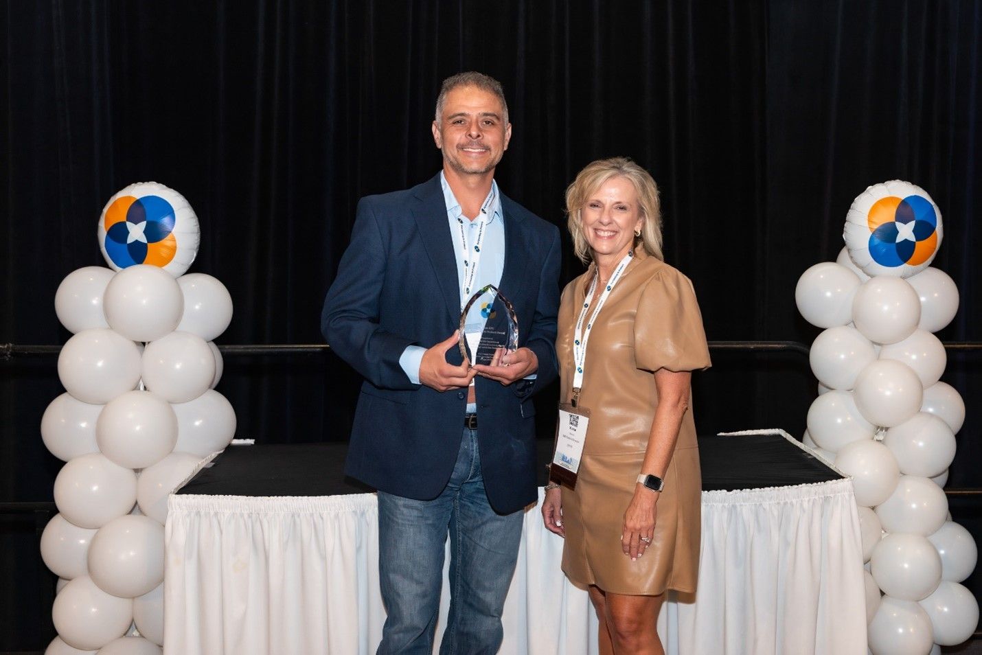 Man with award and woman standing in front of table