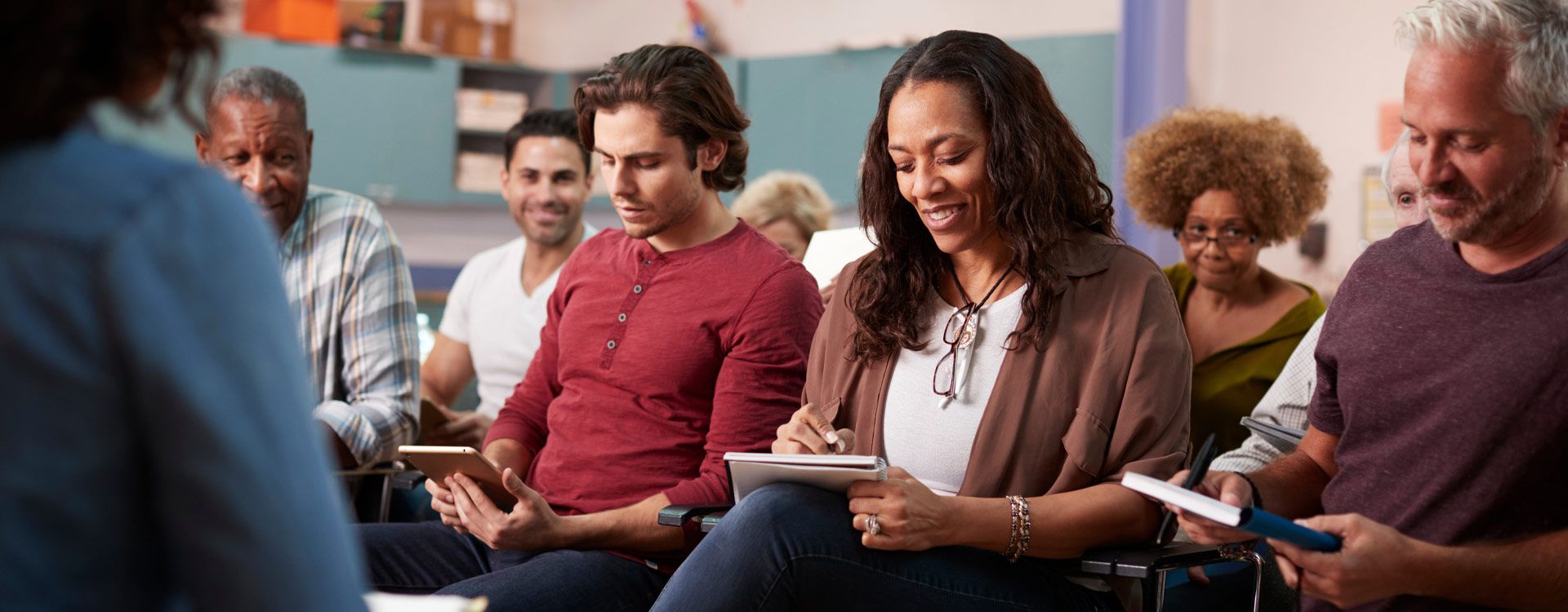 A group of adult students taking notes in a class room